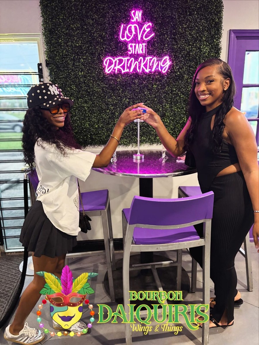 Two friends under a neon sign that reads Say love, start drinking