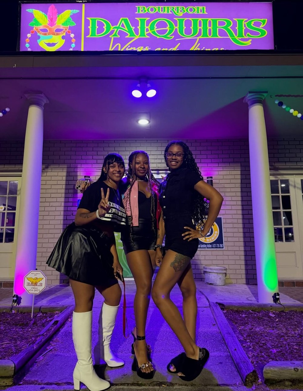 The shop entrance at night, lit in purple and green, under the Bourbon Daiquiris sign